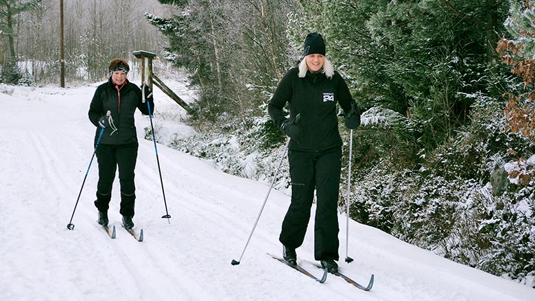 Två kvinnor åker längdåkning på spår i Killeberg