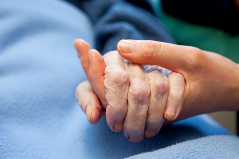 Äldre kvinna håller handen med yngre kvinna