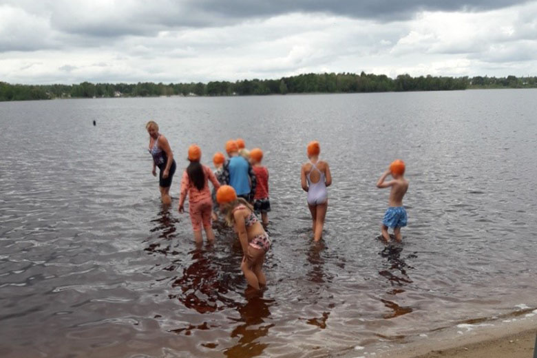 Barn går i vattnet i Osbysjön.