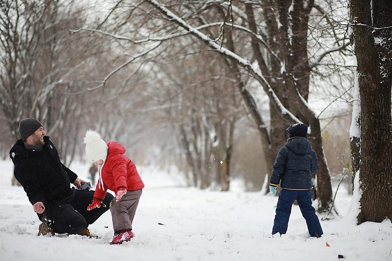 Pappa och två barn leker ute i snön
